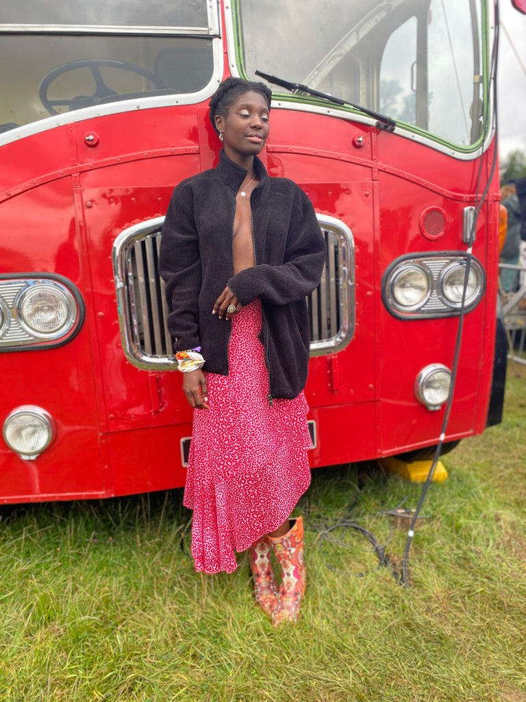 Girl leaning against red bus in bright orange cowboy wellies