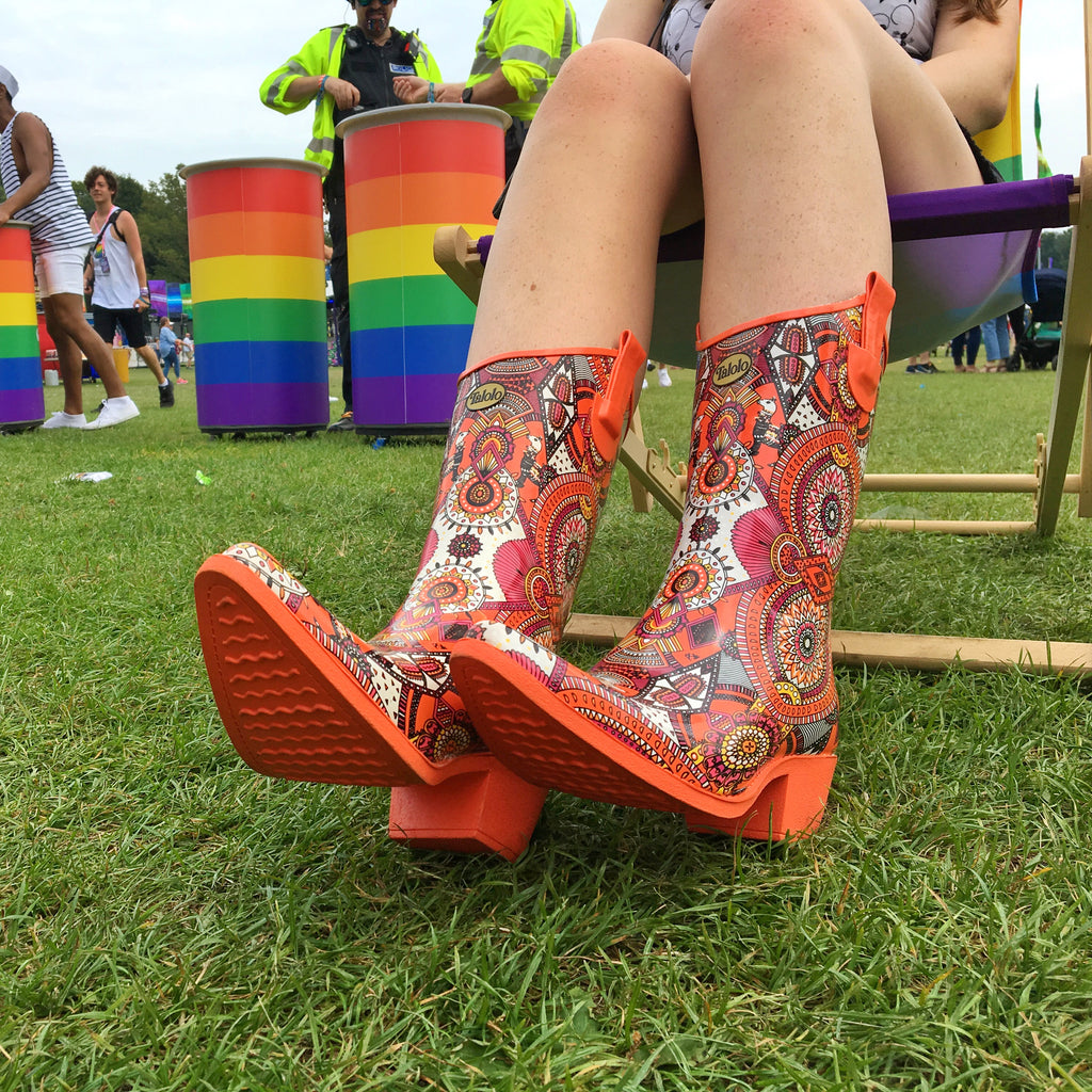 girl in bright orange cowboy wellies sitting on a deck chair at a festival